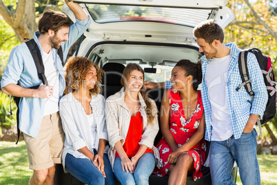 Group of friends on trip sitting in trunk of car