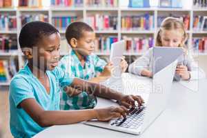 Kids using laptop and digital tablet in library