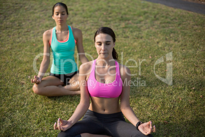 Beautiful women sitting on grass and doing meditation