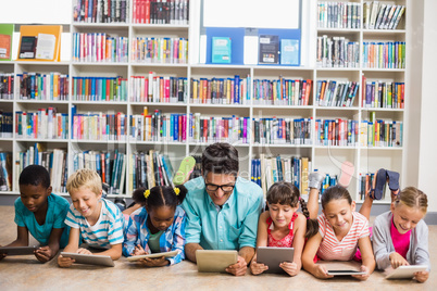 Teacher and kids using digital tablet in library