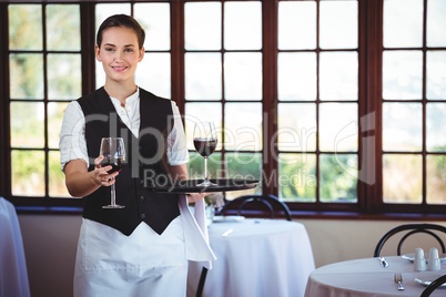 Portrait of smiling waitress offering a glass of red wine