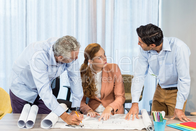 Businesswoman and coworkers discussing blueprint