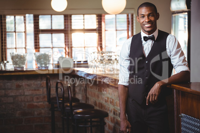 Portrait of bartender standing at bar counter