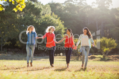 Beautiful women holding hands and walking together in park
