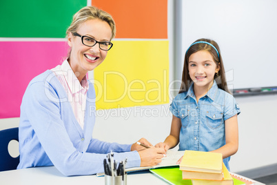 Teacher assisting schoolgirl in drawing