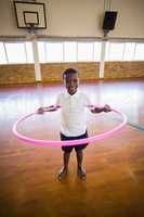 Portrait of boy playing with hula hoop in school gym