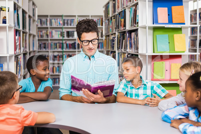 Teacher and kids reading book in library