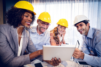 Smiling architects discussing over digital tablet in office