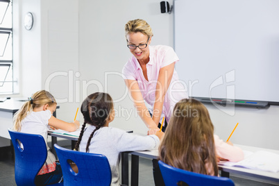 Teacher helping kids with their homework in classroom Teacher helping kids with their homework in classroom