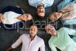 Business team with eyes closed lying on the floor with head toge