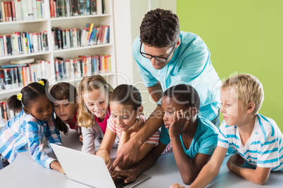 Teacher and kids using laptop in library