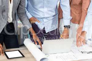 Business people with blueprint on the desk using laptop