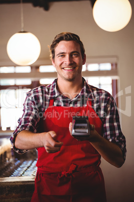 Portrait of waiter showing credit card machine