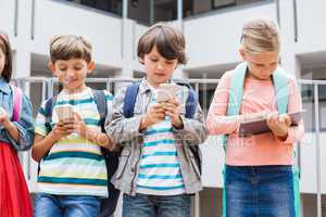 Kids using mobile phone and digital tablet on school terrace