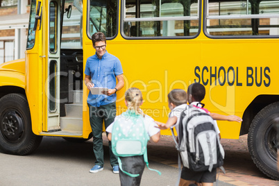 Teacher updating check list of kids while entering in bus