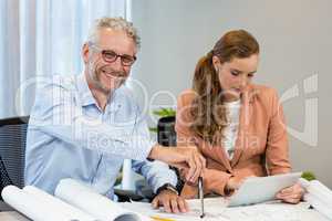 Businesswoman using digital tablet while coworker working on blu