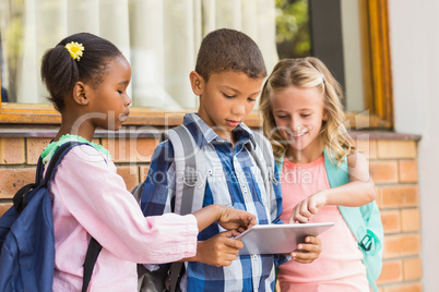 Smiling kids using a  and digital tablet