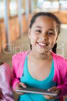 Smiling schoolgirl using digital tablet at school