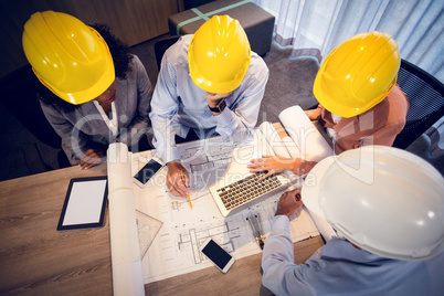 Four architects discussing blueprints in meeting