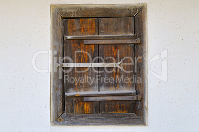 Old wooden window shutters on the clay wall of the house