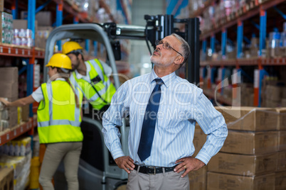 Focus of manager is looking shelves with hands on hips