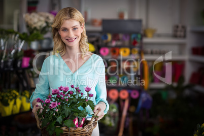 Happy female florist holding basket of flowers