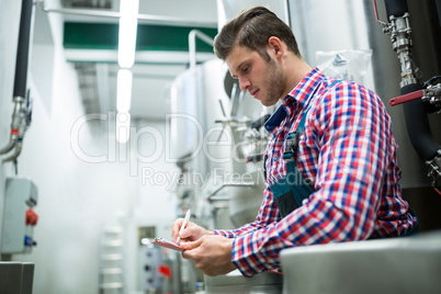 Maintenance worker writing on clipboard
