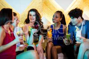 Group of smiling friends interacting while having cocktail