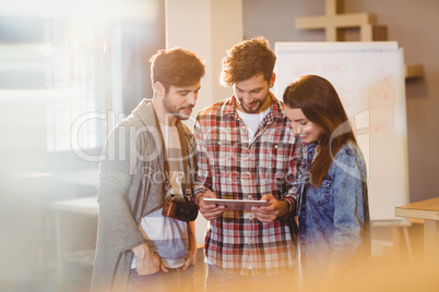 Graphic designer using digital tablet with his coworker