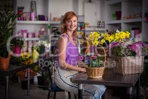 Female florist sitting with basket of flowers