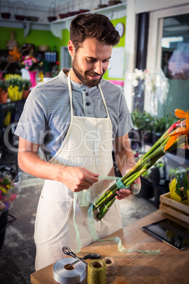 Male florist tying poly ribbon on bunch of flowers