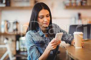 Woman using mobile phone at office cafeteria