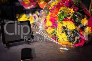 Flower bouquet with smartphone and digital tablet on the table