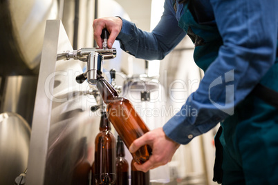 Brewer filling beer in bottle