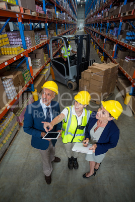 High angle view of worker showing shelves to managers