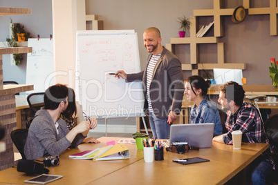 Male graphic designer discussing chart on white board with cowor