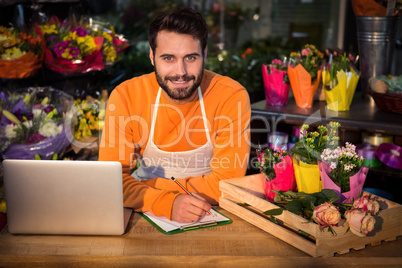 Male florist noting order in notepad
