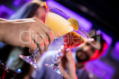 Friends toasting cocktail at bar counter