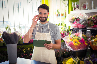 Male florist talking on mobile phone while holding file