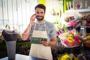 Male florist talking on mobile phone while holding file