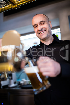 Brewer filling beer in beer glass from beer pump