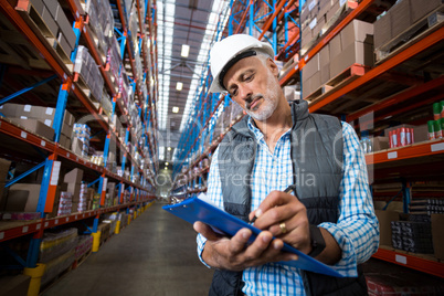 Portrait of worker is writing on clipboard