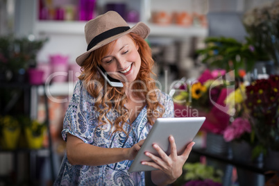 Female florist talking on mobile phone while using digital table