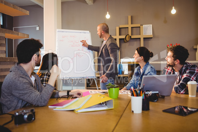 Male graphic designer discussing chart on white board with cowor