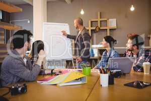Male graphic designer discussing chart on white board with cowor