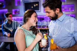 Smiling friends interacting with each other at bar counter while