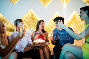 Group of smiling friends toasting a glass of champagne while cel