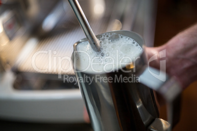 Waiter steaming milk at the coffee machine