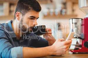 Young man text messaging on mobile phone while having coffee