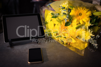 Flower bouquet with smartphone and digital tablet on the table
